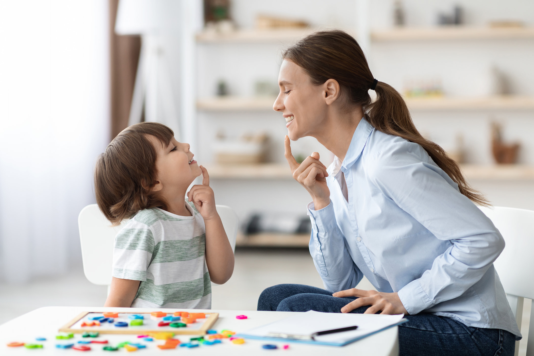 Formation à la parole pour enfants : une orthophonie entraîne un petit garçon, en lui apprenant les exercices de bonne articulation.