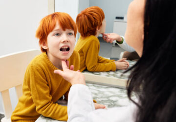Enfant roux en séance d’orthophonie, observé par une professionnelle