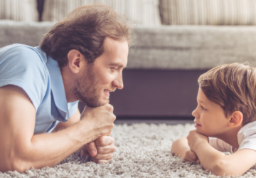 Père et enfant allongés face à face, illustrant l’importance de l’interaction parent-enfant dans le développement du langage