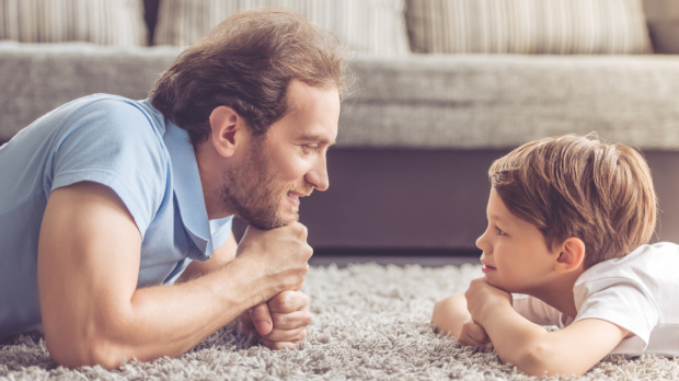 Père et enfant allongés face à face, illustrant l’importance de l’interaction parent-enfant dans le développement du langage