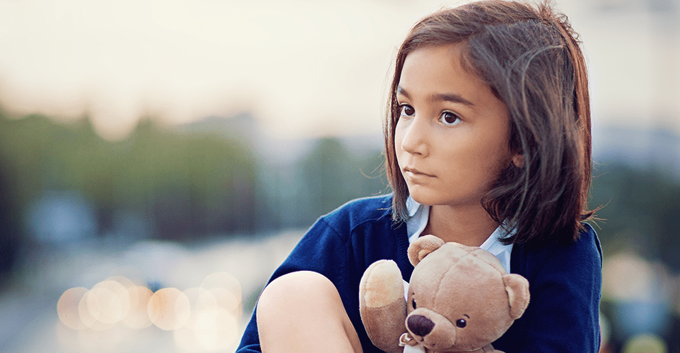 Enfant pensive tenant un ourson en peluche, illustrant les effets des difficultés langagières sur la confiance en soi.