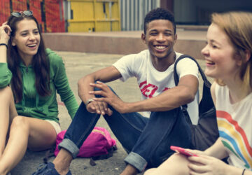 Groupe d’adolescents qui discutent et rient ensemble, illustrant l’importance du langage dans les relations sociales.